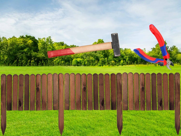 Holzzaun mit Hammer und Drahtschneider im Garten