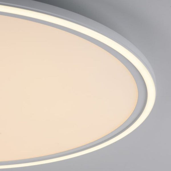 Ovaler Badezimmerspiegel mit integrierter LED Beleuchtung und Touch Sensor an einer mit rechteckigen Fliesen verkleideten Wand über einem Waschbecken.