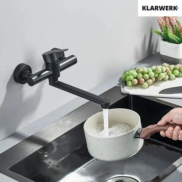 Wandarmatur für die Küche von Klarwerk mit schwenkbarem Auslauf über einem Spülbecken beim Befüllen eines Topfes.