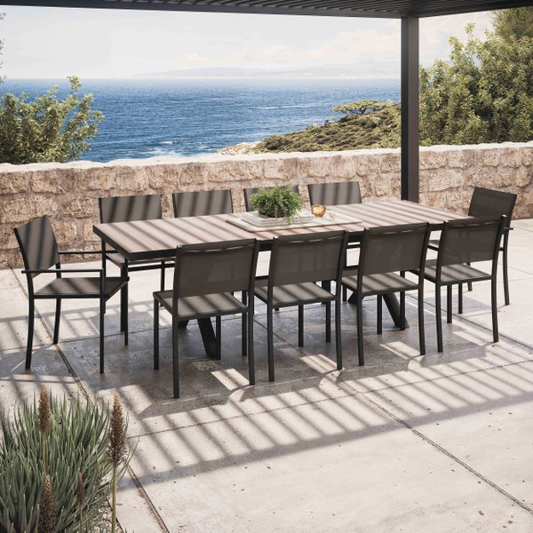 Großes Gartenmöbel-Set mit Holztisch und zehn schwarzen Stühlen auf einer Terrasse mit Meerblick unter einer Pergola.