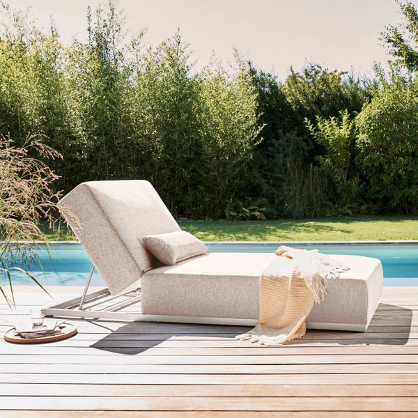 Polster-Gartenliege mit verstellbarer Rückenlehne auf einer Holzterrasse am Pool mit dichter grüner Bepflanzung.