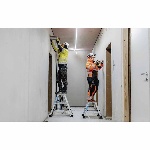 Zwei Handwerker arbeiten auf Trittleitern in einem hellen Flur.