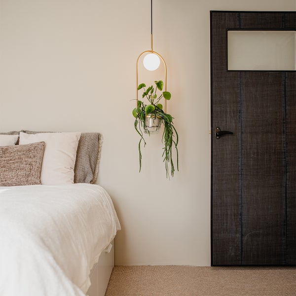 Schlafzimmer mit Bett und einer Hängeleuchte mit integriertem Pflanzenhalter