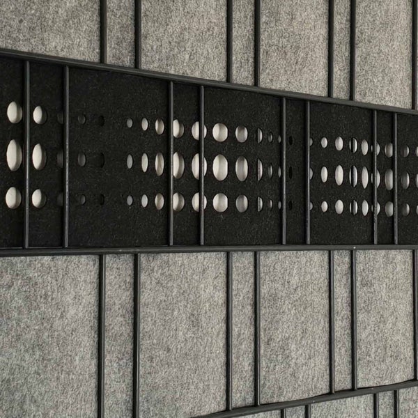 Detailaufnahme eines Akustikpaneels mit runden Aussparungen in einem Metallrahmen