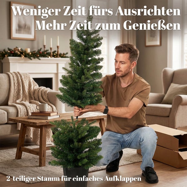 Ein Mann baut einen künstlichen Weihnachtsbaum in einem Wohnzimmer zusammen, der aus zwei Teilen besteht und ein einfaches Aufklappen ermöglicht.
