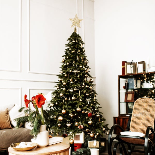 Weihnachtsbaum mit Christbaumschmuck, Stern und Geschenken im Wohnzimmer.