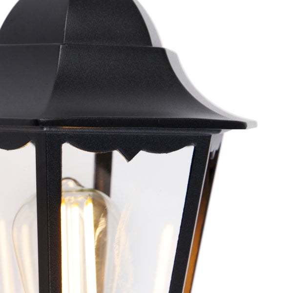 Nahaufnahme einer schwarzen Außenwandleuchte im klassischen Laternenstil mit LED-Filament-Leuchtmittel und Klarglas.