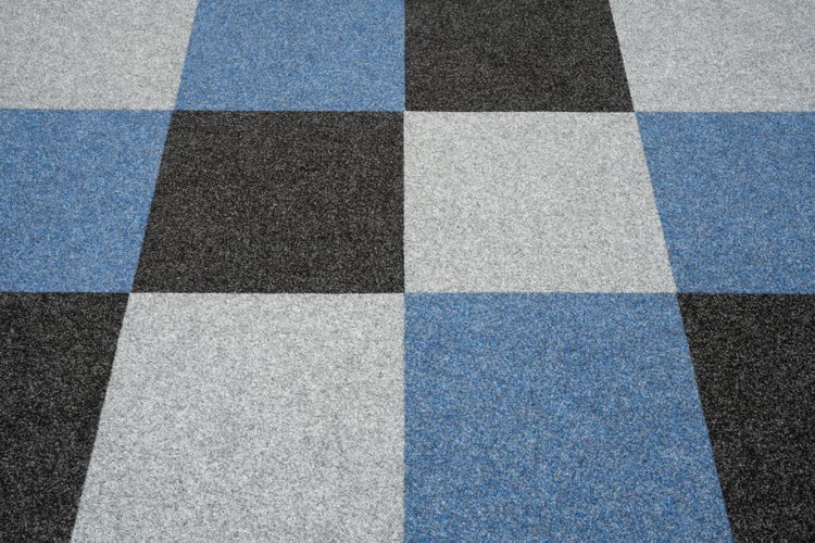 Schachbrettmuster aus quadratischen Teppichfliesen in verschiedenen Farben.