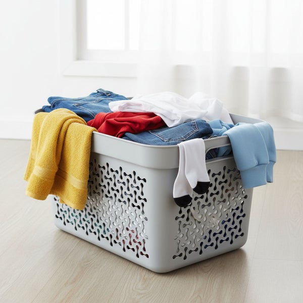 Wäschekorb aus Kunststoff gefüllt mit Kleidung vor einem Fenster