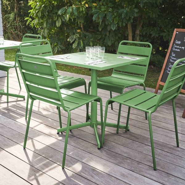 Grüne Gartenmöbel-Garnitur aus Metall mit einem quadratischen Tisch und vier Lattenstühlen auf einer Holzterrasse.
