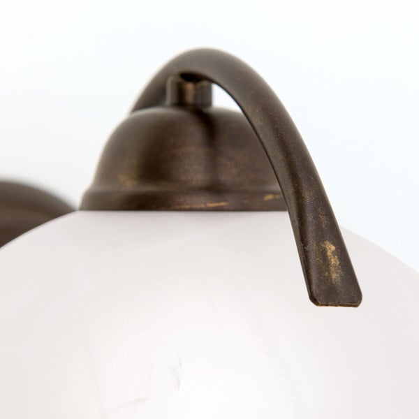 Detailansicht einer Wandleuchte mit kugelförmigem Lampenschirm aus Glas und einem Halterungsarm aus Metall im rustikalen Stil