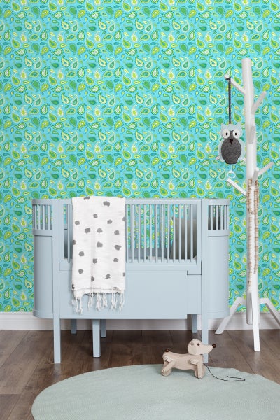 Babyzimmer mit blauem Kinderbett, gemusterter Tapete und dekorativen Accessoires.