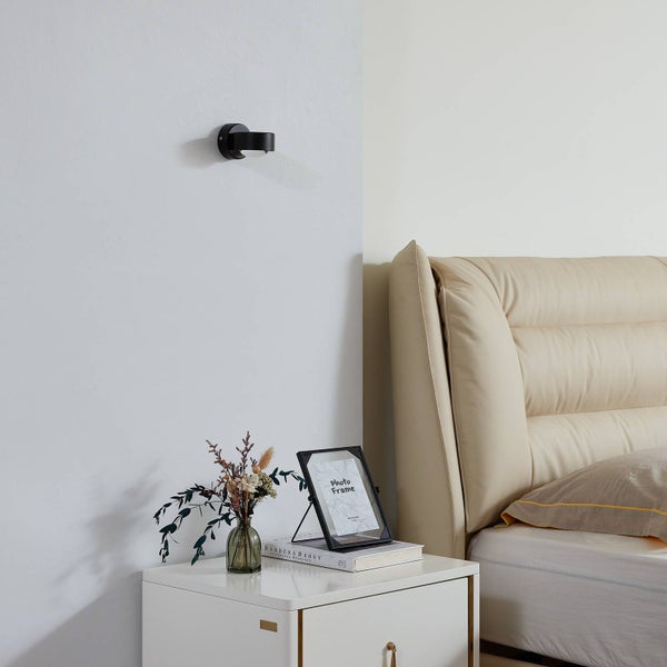 Nachttisch mit Dekoration und einer Wandleuchte im Schlafzimmer