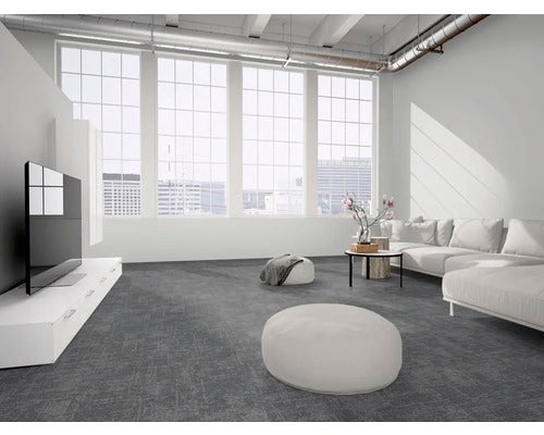 Modernes Wohnzimmer mit dunkelgrauen texturierten Teppichfliesen, weißem Sofa und großen Fenstern im industriellen Loft-Stil.