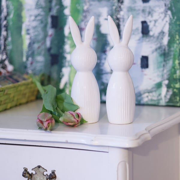 Zwei weiße Keramikhasen als Dekoration auf einem weißen Tisch