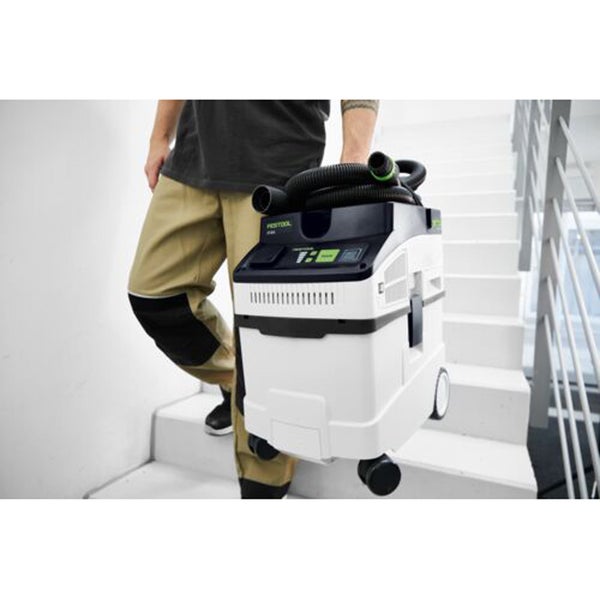 Eine Person trägt einen Festool Industriestaubsauger eine Treppe hinunter.