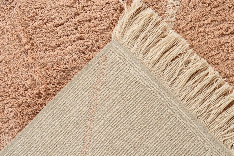 Detailaufnahme eines Hochflor-Teppichs mit Fransen und gewebter Unterseite.