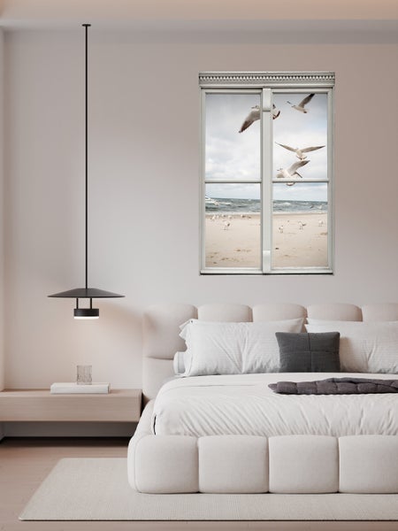 Helles Schlafzimmer mit Doppelbett, Nachttisch, Lampe und Fenster mit Blick auf einen Strand mit Möwen