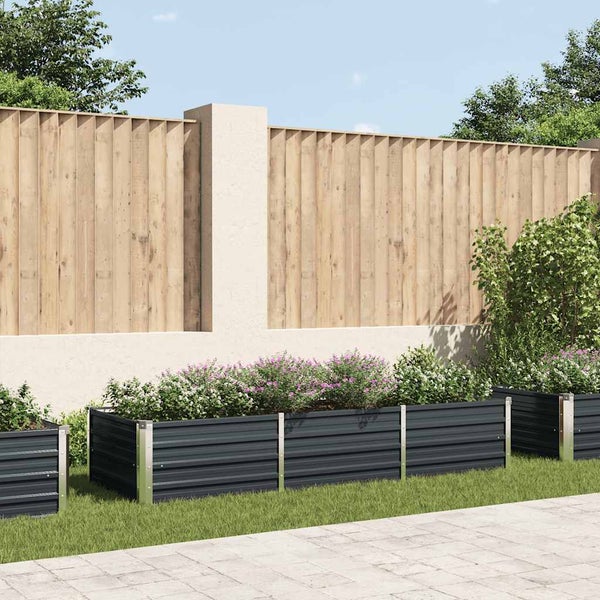 Anthrazitfarbenes Hochbeet aus Metall mit Blumen in einem hellen Garten vor einem Sichtschutzzaun aus Holz.