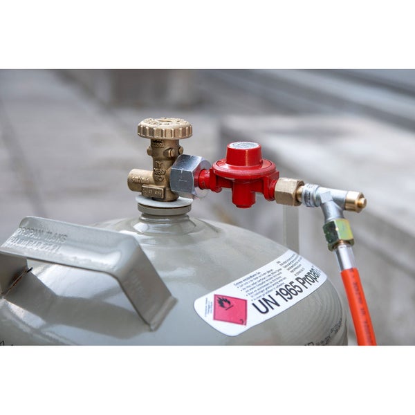 Propangasflasche mit montiertem Druckregler und Gasschlauch an einem Messingventil.