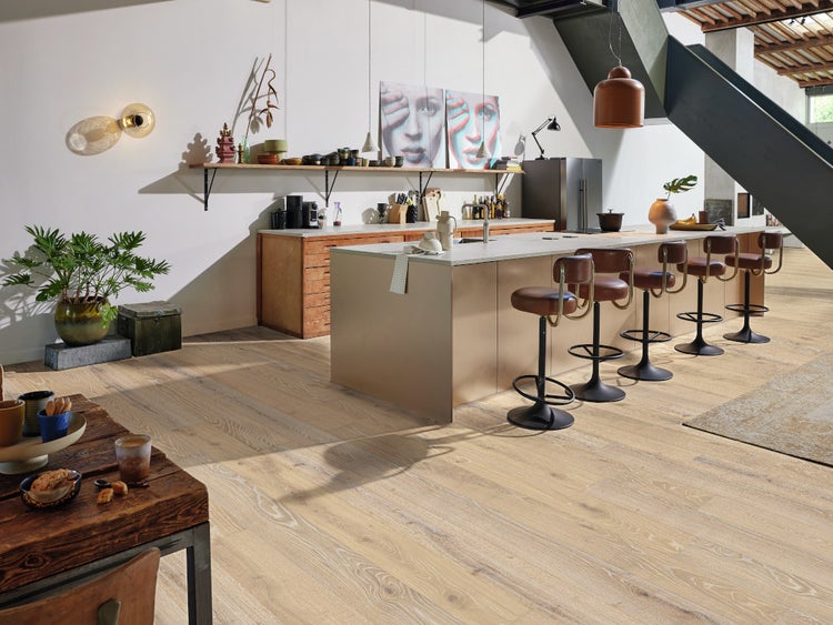 Helle Wohnküche mit moderner Kochinsel, Barhockern aus Leder und Parkettboden aus Eiche im Landhausdielen-Stil.
