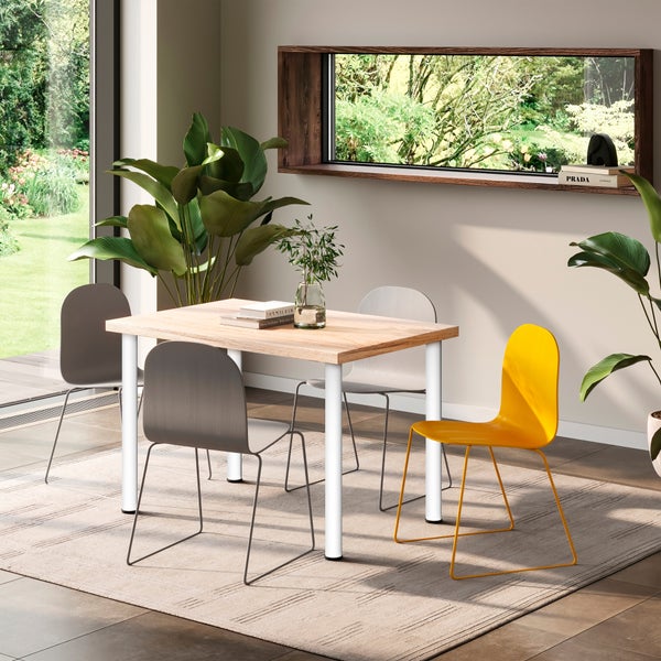 Esszimmer mit einem Esstisch aus Holz mit Tischbeinen aus Metall, kombiniert mit Stühlen in verschiedenen Designs und Zimmerpflanzen.