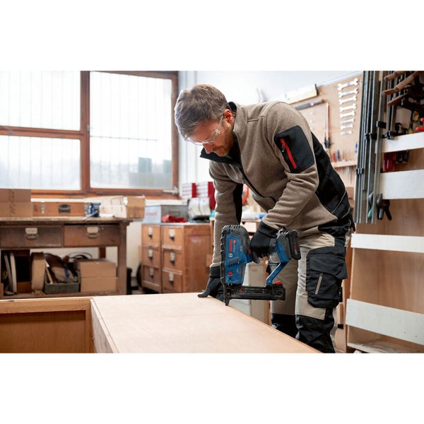 Ein Mann verwendet einen Akku-Nagler in einer Werkstatt.