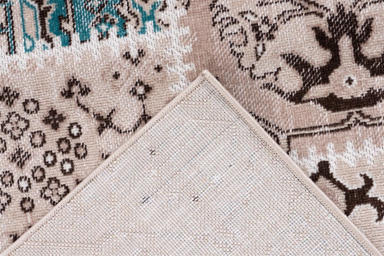 Nahaufnahme eines Teppichs im Vintage-Stil mit gewebtem Muster und umgeschlagener Ecke, die die Unterseite zeigt.