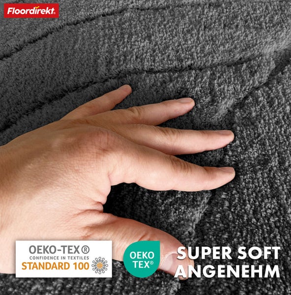 Detailansicht eines grauen Teppichs mit Hand und den Logos von Floordirekt und OEKO-TEX Standard 100, die für textile Sicherheit stehen.