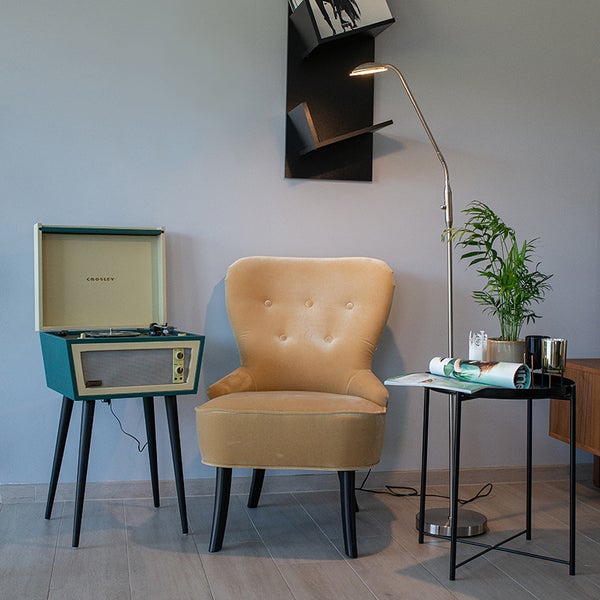 Wohnzimmer mit Sessel, Stehlampe, Plattenspieler und Beistelltisch