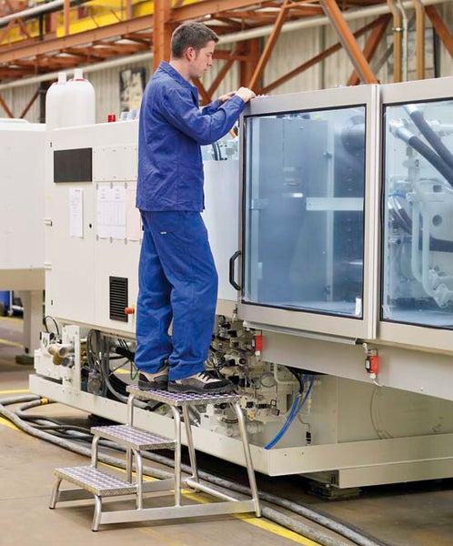 Mann auf einer dreistufigen Arbeitsbühne aus Aluminium, der eine Maschine bedient