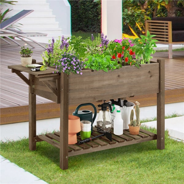 Hochbeet aus Holz mit Pflanzen, Gartengeräten und Ablagefläche