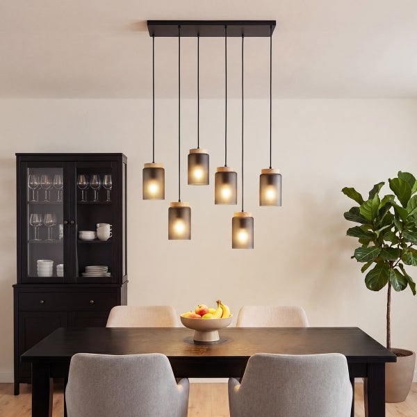 Modernes Esszimmer mit einer 7-flammigen Pendelleuchte aus Rauchglas und Holz über einem dunklen Esstisch mit hellgrauen Stühlen.