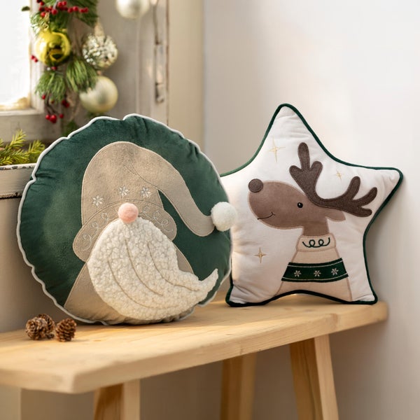 Zwei dekorative Weihnachtskissen in runder und sternförmiger Ausführung mit weihnachtlichen Motiven auf einer Holzbank.