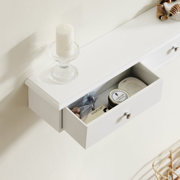 Weißes Wandregal mit Schublade, darauf Kerze in einem Kerzenhalter