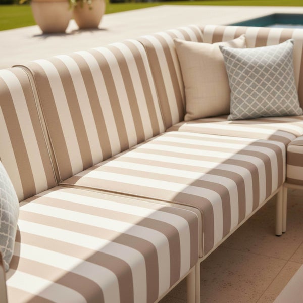 Gestreiftes Gartensofa mit Zierkissen in einem hellen Außenbereich auf einer Terrasse am Pool.
