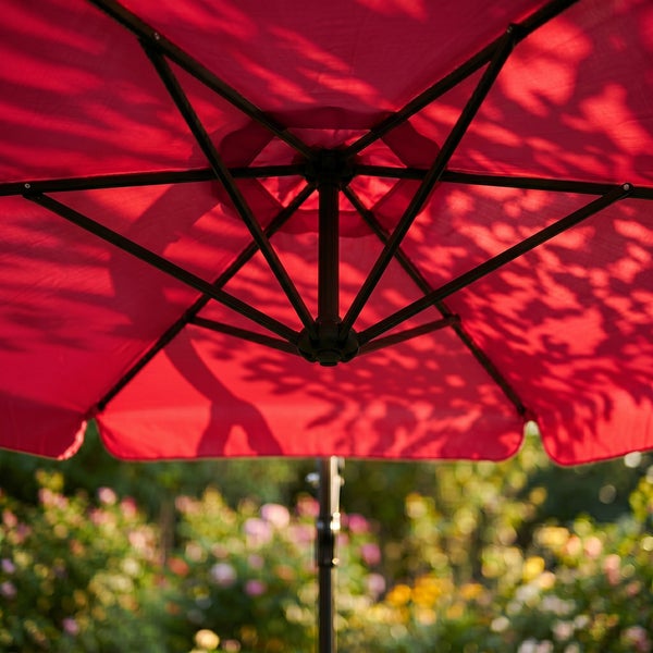 Roter Sonnenschirm von unten betrachtet mit stabilem Metallgestänge und Stoffbespannung in einem Garten.
