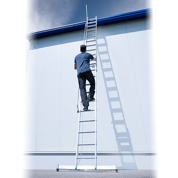 Eine Person steigt eine Aluminiumleiter an einer Fassade hinauf.