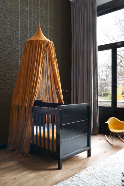 Kinderzimmer mit schwarzem Gitterbett und Baldachin