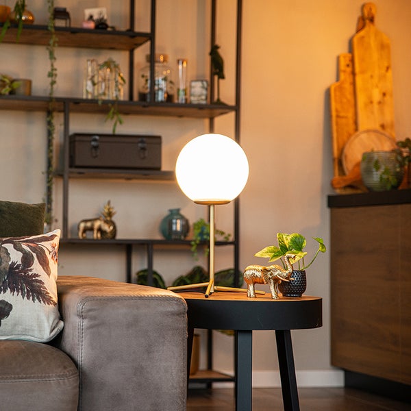 Dekoratives Wohnzimmer mit beleuchteter Kugel-Tischleuchte auf Beistelltisch