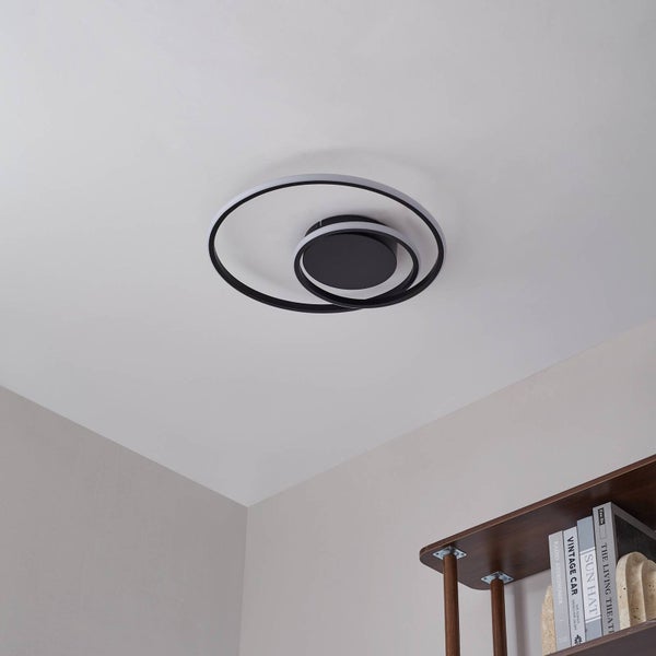 Moderne LED-Deckenleuchte in Schwarz mit drei konzentrischen Ringen, in einem hellen Zimmer montiert.