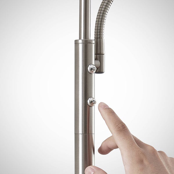 Detailansicht einer Küchenarmatur aus gebürstetem Metall, bei der ein Finger einen der zwei Knöpfe drückt.
