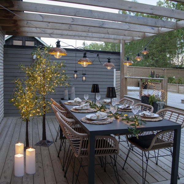 Terrasse mit Esstisch, Stühlen, Beleuchtung und Dekorationen für eine stimmungsvolle Atmosphäre