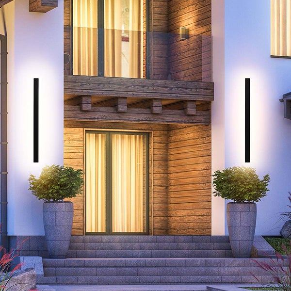 Moderne Hausfassade mit zwei schlanken Aussenwandleuchten und bepflanzten Steintrögen