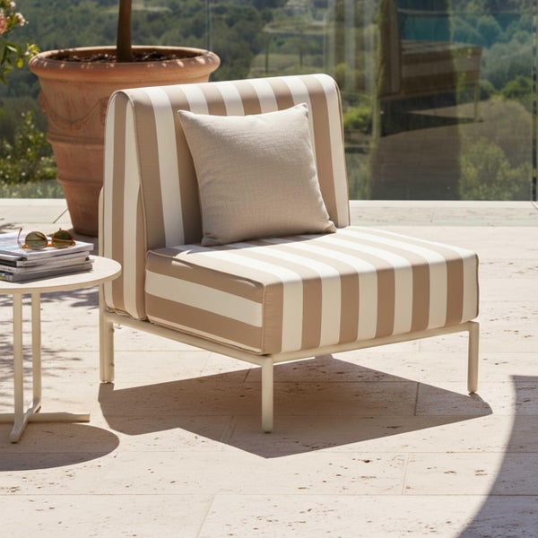Moderner Garten-Loungesessel mit gestreiftem Polster und Dekokissen auf einer Terrasse neben einem Beistelltisch.