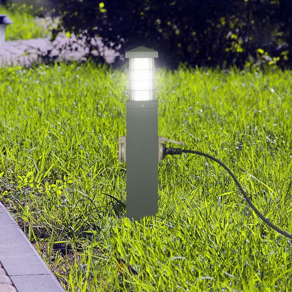 Graue Steckdosensäule mit integrierter LED-Leuchte im Garten auf grünem Rasen, mit eingestecktem Kabel.