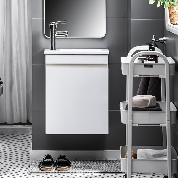 Badezimmer mit Waschbeckenunterschrank, Spiegel, Regalwagen und Badematte