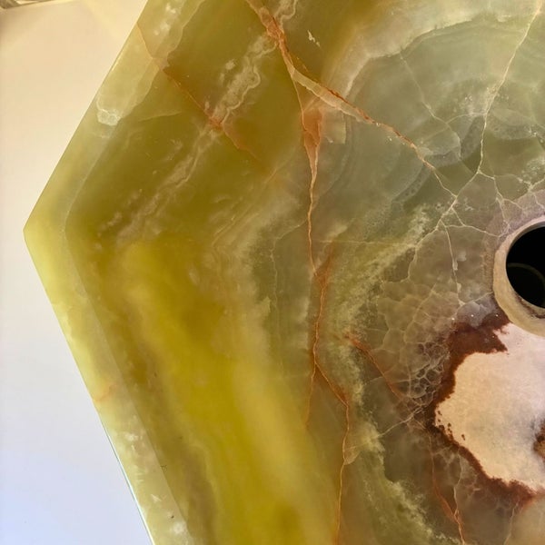 Nahaufnahme eines sechseckigen Waschbeckens aus Onyx-Naturstein mit natürlicher Maserung und Abflussöffnung.