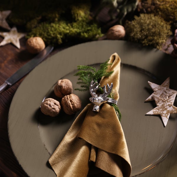 Dekorativer Essteller mit Serviette, Serviettenring in Hirschform, Tannenzweig und Walnüssen.
