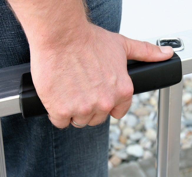 Eine Hand hält eine Aluminiumleiter mit schwarzem Griff.